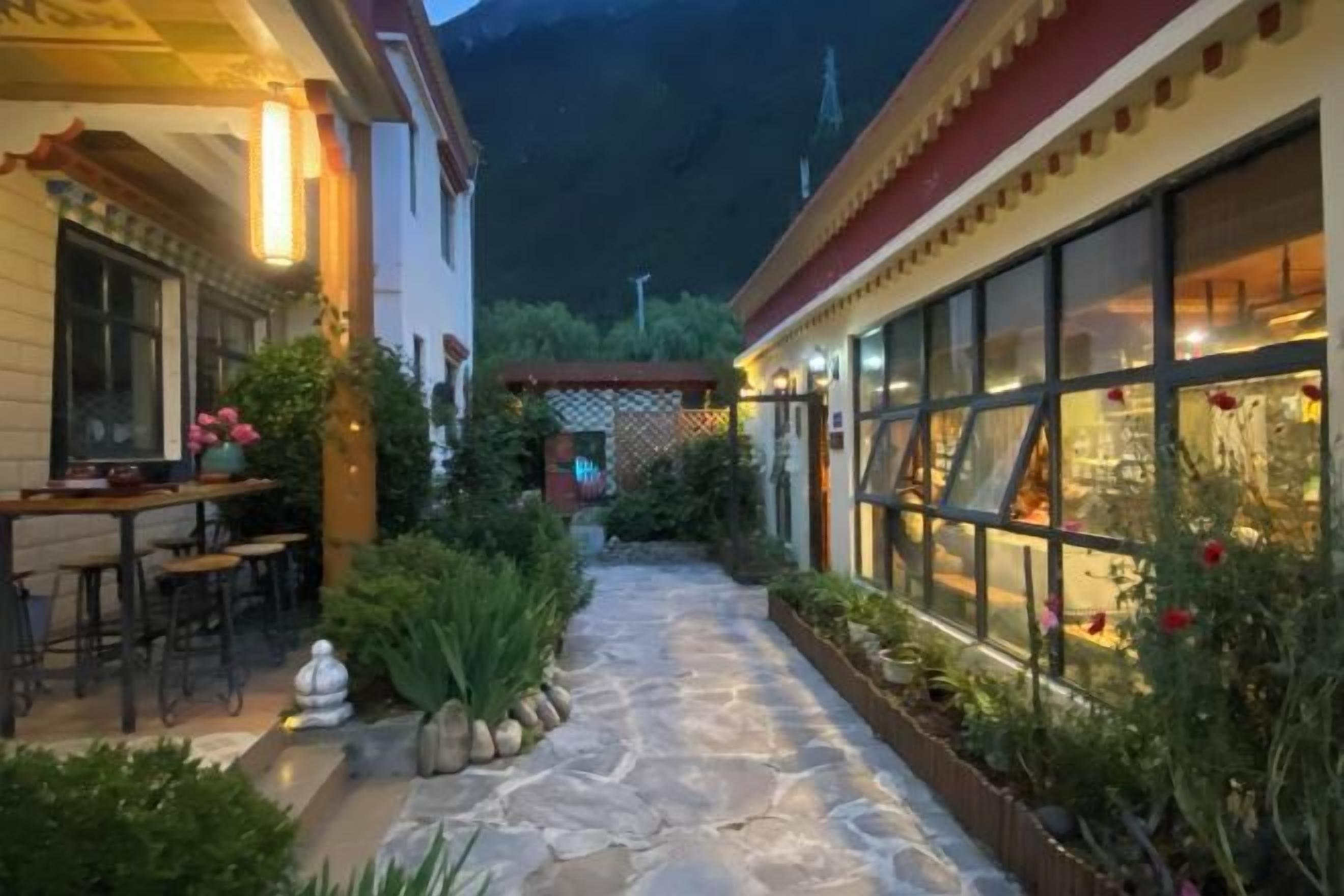 Un patio con suelo de piedra, una zona de comedor y un edificio con grandes ventanales.