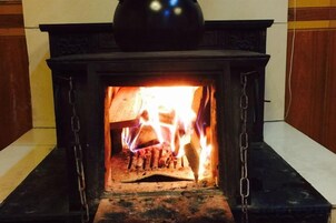 Una chimenea con fuego encendido, rodeada por una repisa negra y un marco de madera.