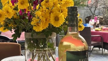 Una mesa con una botella de Jerez Dulce de las Indias Orientales y un jarrón con flores amarillas.