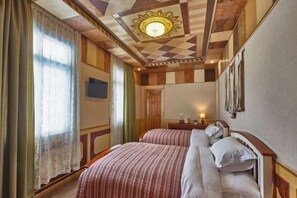 Een hotelkamer met twee bedden, een houten plafond en een groot raam met gordijnen.
