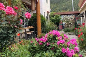 Een tuin met roze bloemen en een tafel voor een gebouw.