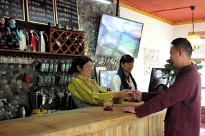 En bardisk med en avlång yta, hyllor med flaskor och en tv-skärm.