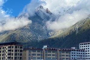 Een hotel met meerdere verdiepingen, een bergachtig landschap en een heldere lucht.