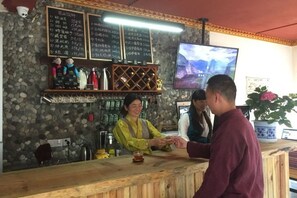 Zona de bar con pared de piedra, mostrador de madera y pizarras con el menú.