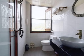 A bathroom with a toilet, a large sink, a window, and a shower area. - Longxingtang (Huangshan City)