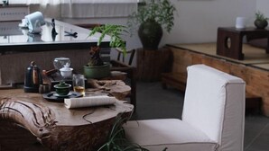 A cozy room with a wooden table, a white chair, a potted plant, and a window with curtains. - Longxingtang (Huangshan City)