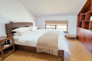 A bedroom with a wooden bed, a nightstand, a window with blinds, and a built-in wooden shelf. - Longxingtang (Huangshan City)