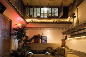 A traditional interior with a tiled ceiling, a wooden bench, and a small table with a lamp.