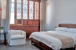 A bedroom with a bed, a chair, a window with a wooden lattice design, and a curtain. - Longxingtang (Huangshan City)