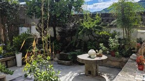 A garden with a stone table, potted plants, and a wooden fence. - Longxingtang (Huangshan City)