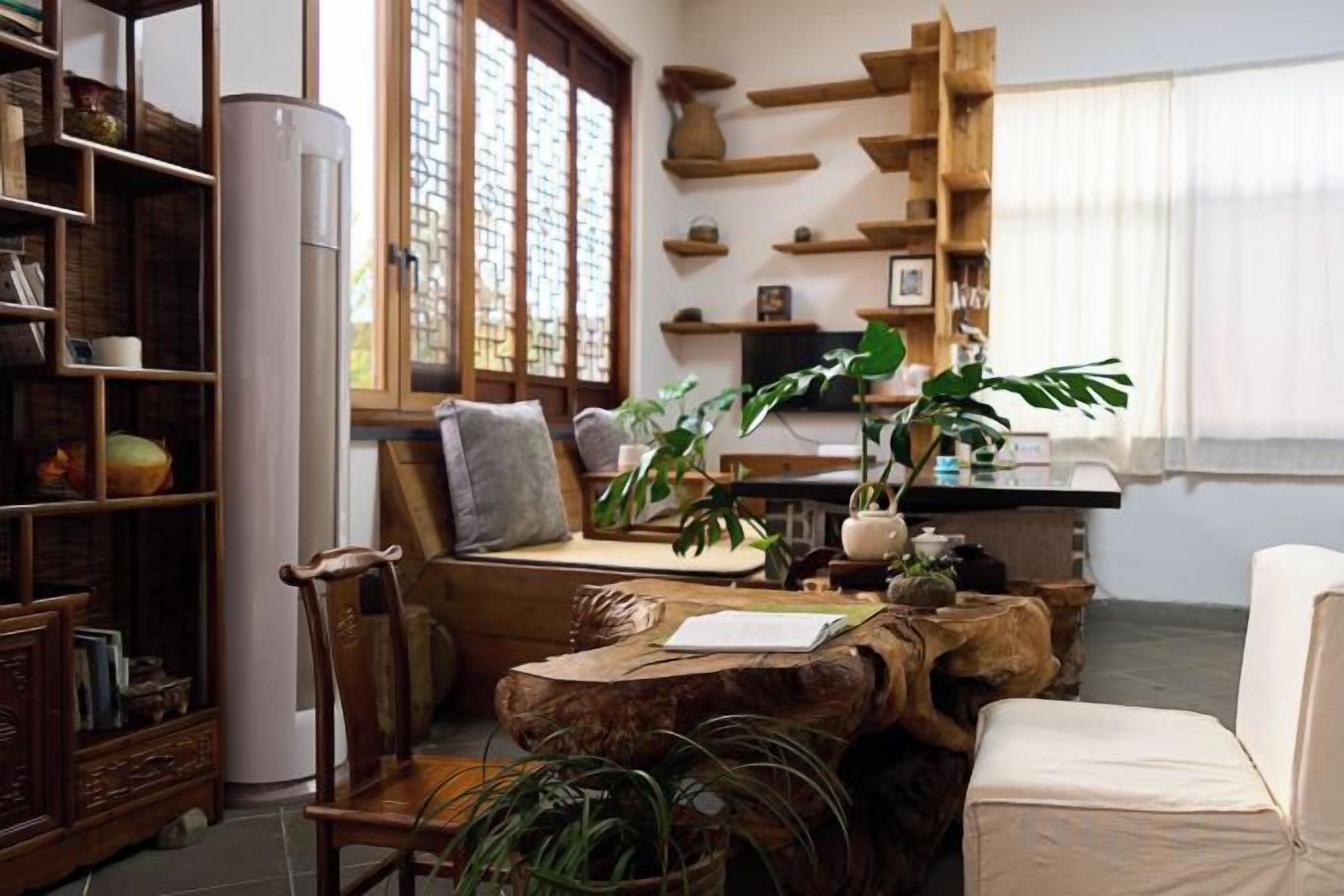 Una sala de estar acogedora con una estantería de madera, un sofá cómodo, una mesa de comedor con sillas y un ventanal con estantes de madera decorativos.