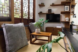 A traditional Japanese-style living room with tatami flooring, a low wooden table, and a television on the wall. - Longxingtang (Huangshan City)