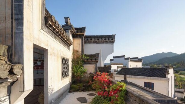 A traditional courtyard with stone steps, a white building with a tiled roof, and a view of distant mountains. - Longxingtang (Huangshan City)