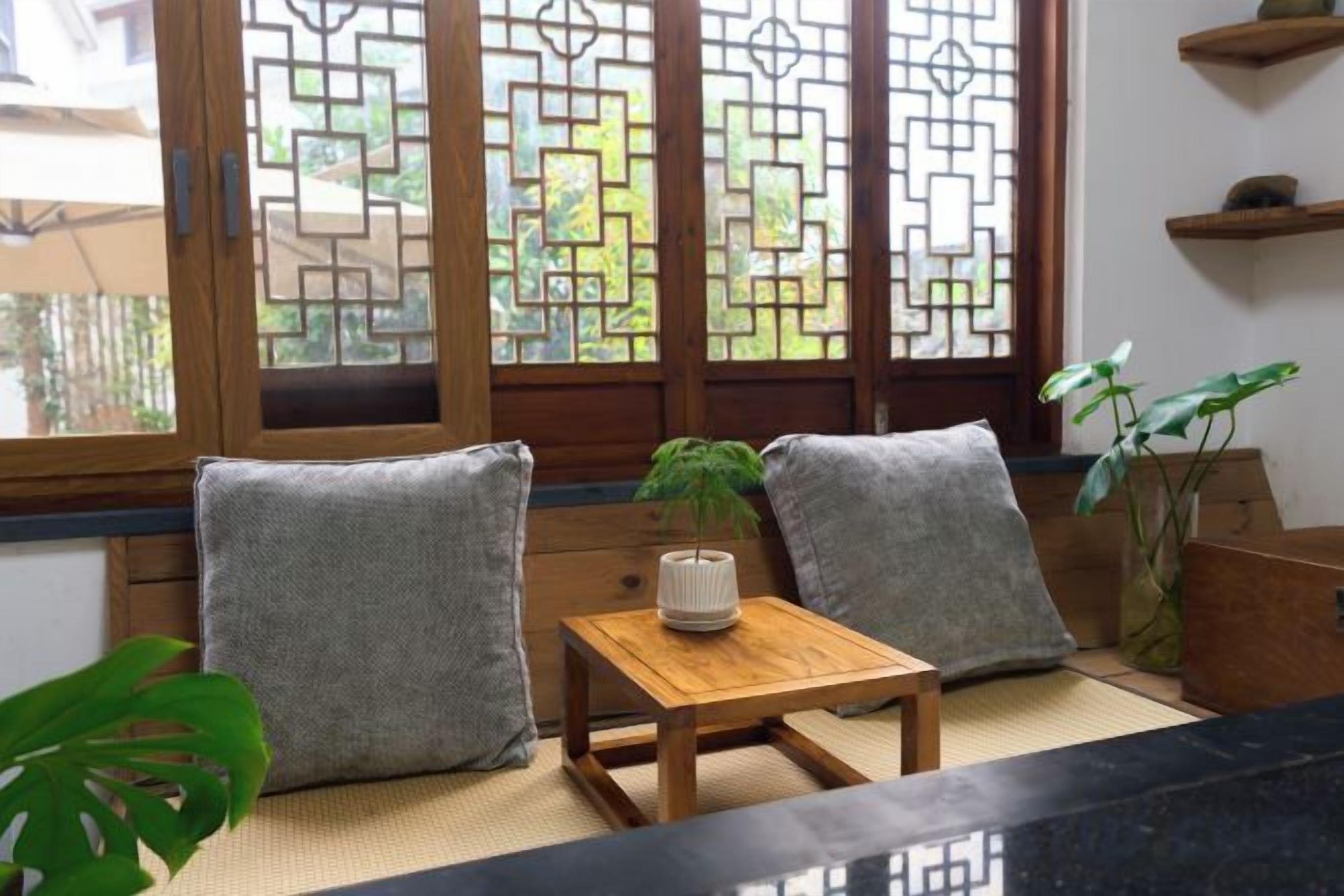 Une pièce dotée d’un sol recouvert de tatamis, d’une basse table en bois ornée d’une plante et de portes coulissantes traditionnelles de style japonais.