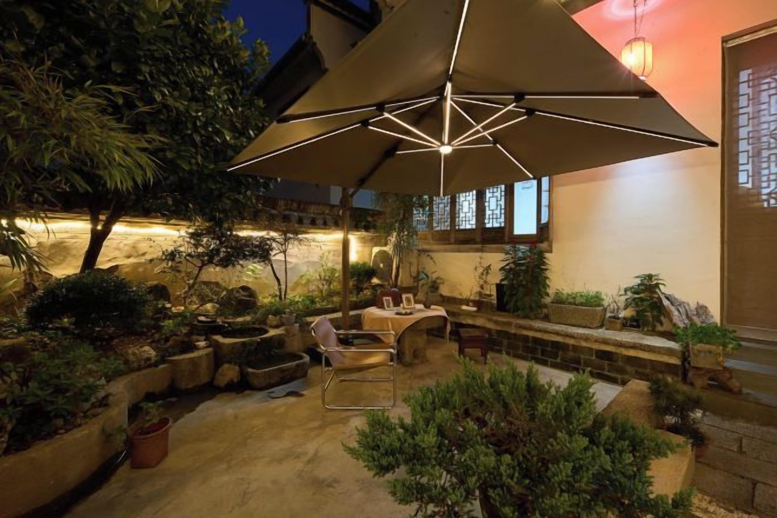 An outdoor patio with a large umbrella, seating, and potted plants.