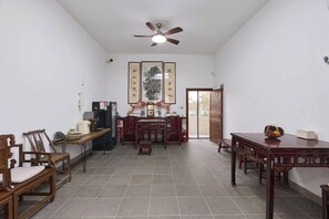A spacious room with a ceiling fan, a dining table, chairs, and a refrigerator. - Longxingtang (Huangshan City)