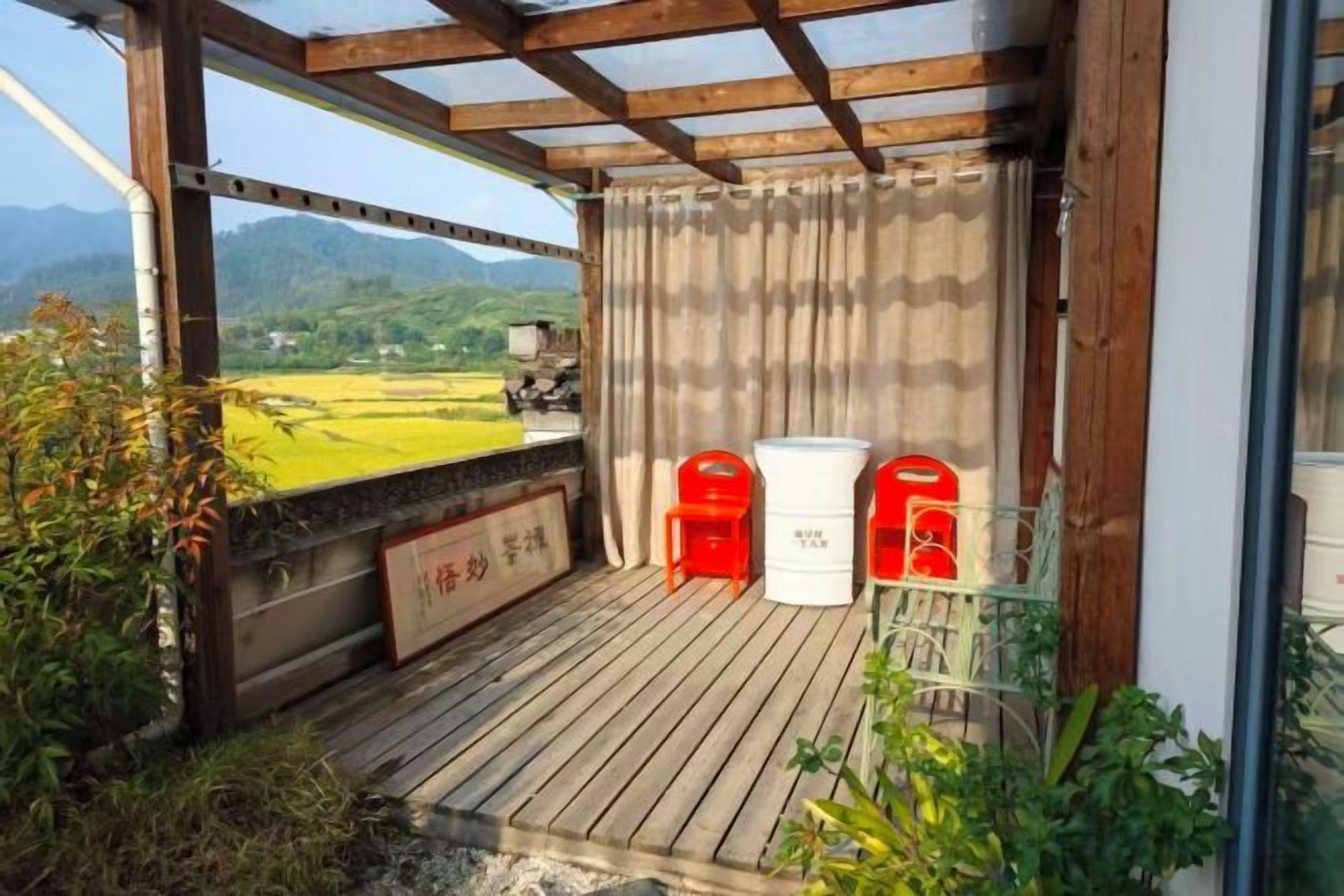 A wooden deck with a view of a green landscape, two white chairs, and a red object.
