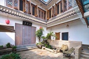 A traditional courtyard with a wooden gate, potted plants, and a seating area. - Longxingtang (Huangshan City)