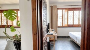 A room with a bed, a desk, a potted plant, and a window with curtains. - Longxingtang (Huangshan City)