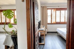 A room with a bed, a desk, a potted plant, and a window with curtains. - Longxingtang (Huangshan City)