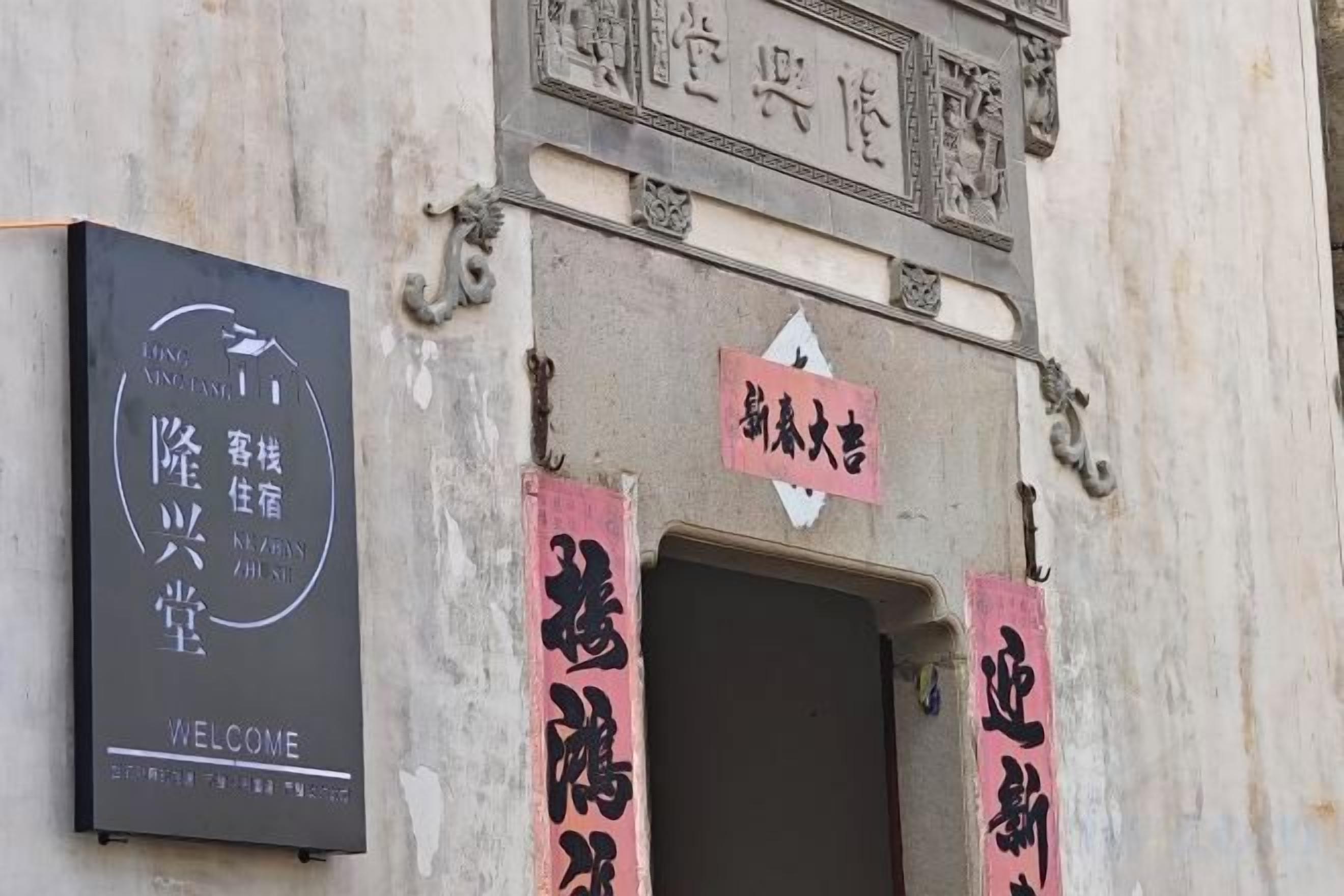 A building entrance with a sign that reads 'Welcome' and another sign with Chinese characters.
