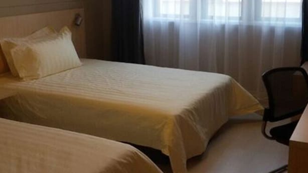 A hotel room with two beds, a chair, and a window with curtains. - Jinjiang Inn (Tianjin)