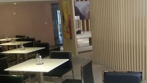 A restaurant with tables and chairs, a counter, and a vertical striped wall. - Jinjiang Inn (Tianjin)