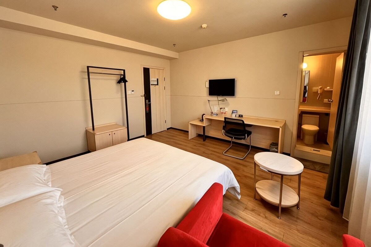 Ein Hotelzimmer mit einem Bett, einem Schreibtisch, einem Stuhl, einem Fernseher und einem Badezimmer.