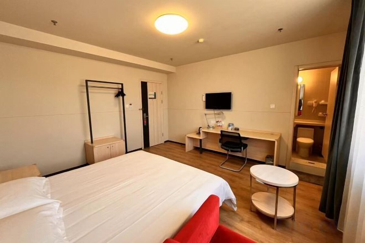 A hotel room with a bed, desk, chair, and a small round table.