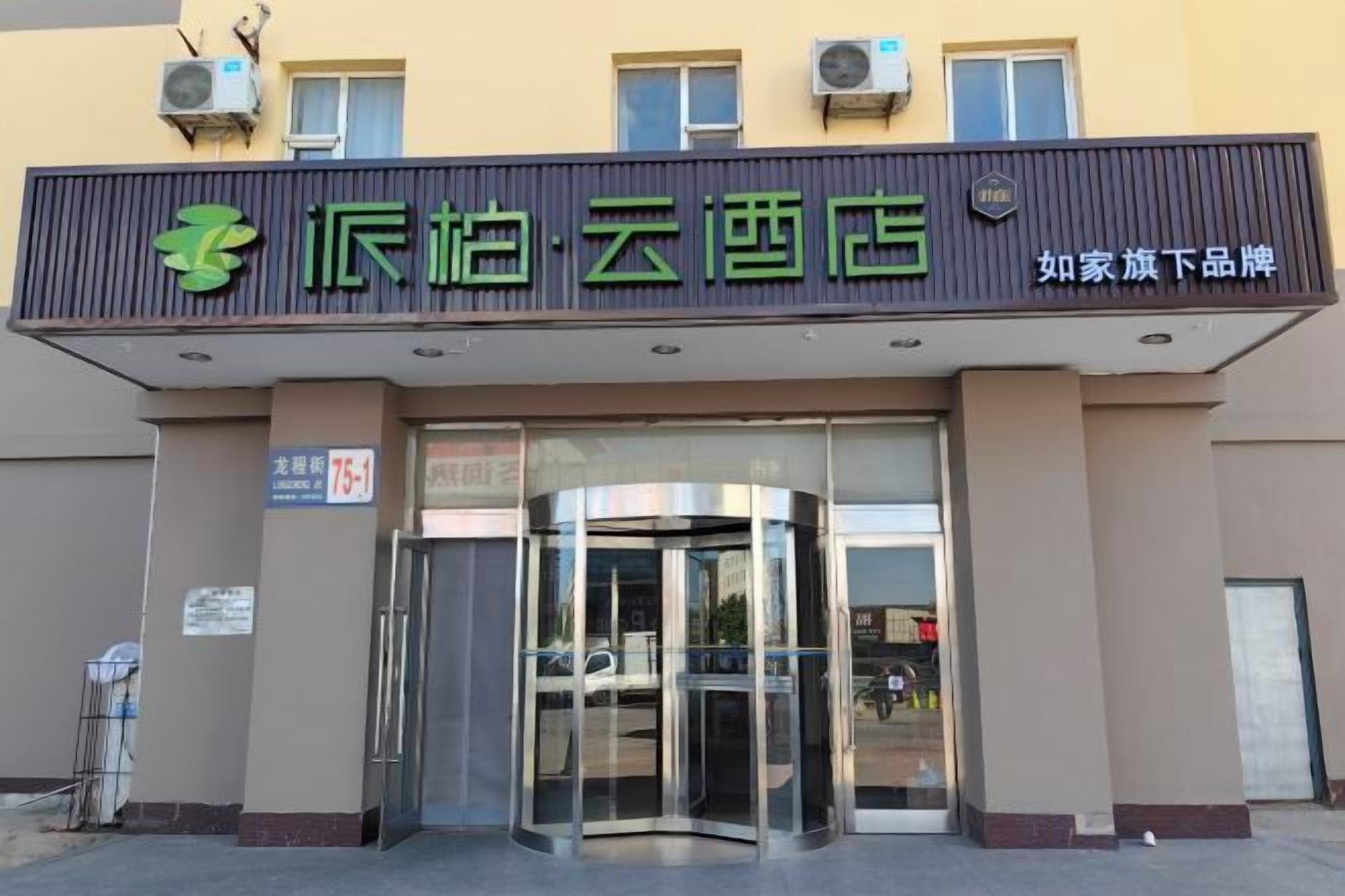 A hotel entrance with a signboard, a revolving door, and a clear glass facade.