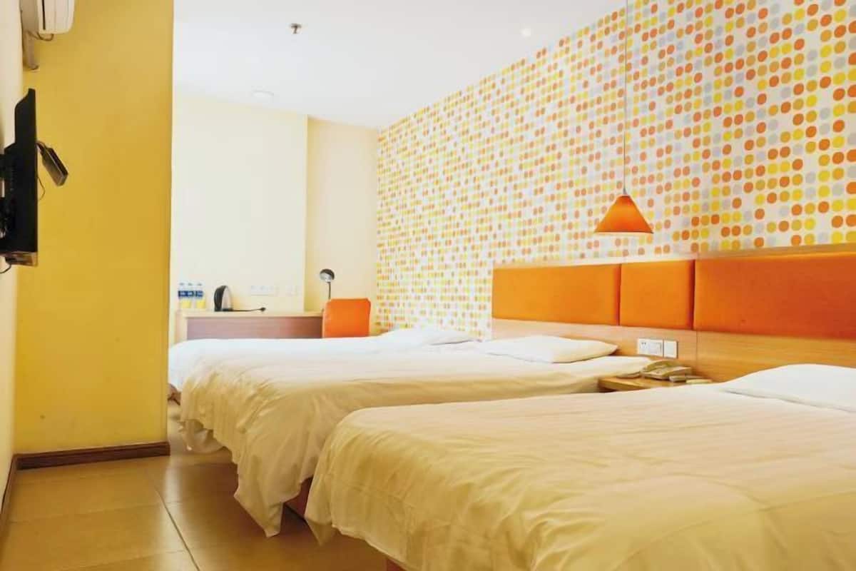 A hotel room with two beds, a wall with a polka dot pattern, and an orange headboard.
