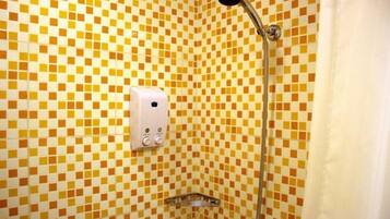 Un baño con piso de baldosas a cuadros, ducha de mano y dispensador de jabón.