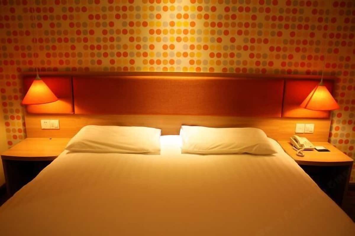 A hotel room with a bed, two bedside lamps, a nightstand, and a polka dot wallpaper.