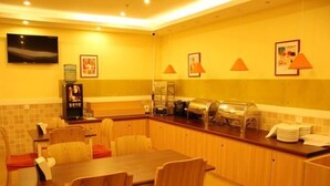 A hotel dining area with a long counter, multiple chairs, a television mounted on the wall, and several framed pictures. - Homeinn Pebble Hotel (Huludao Passenger Terminal) (Huludao)