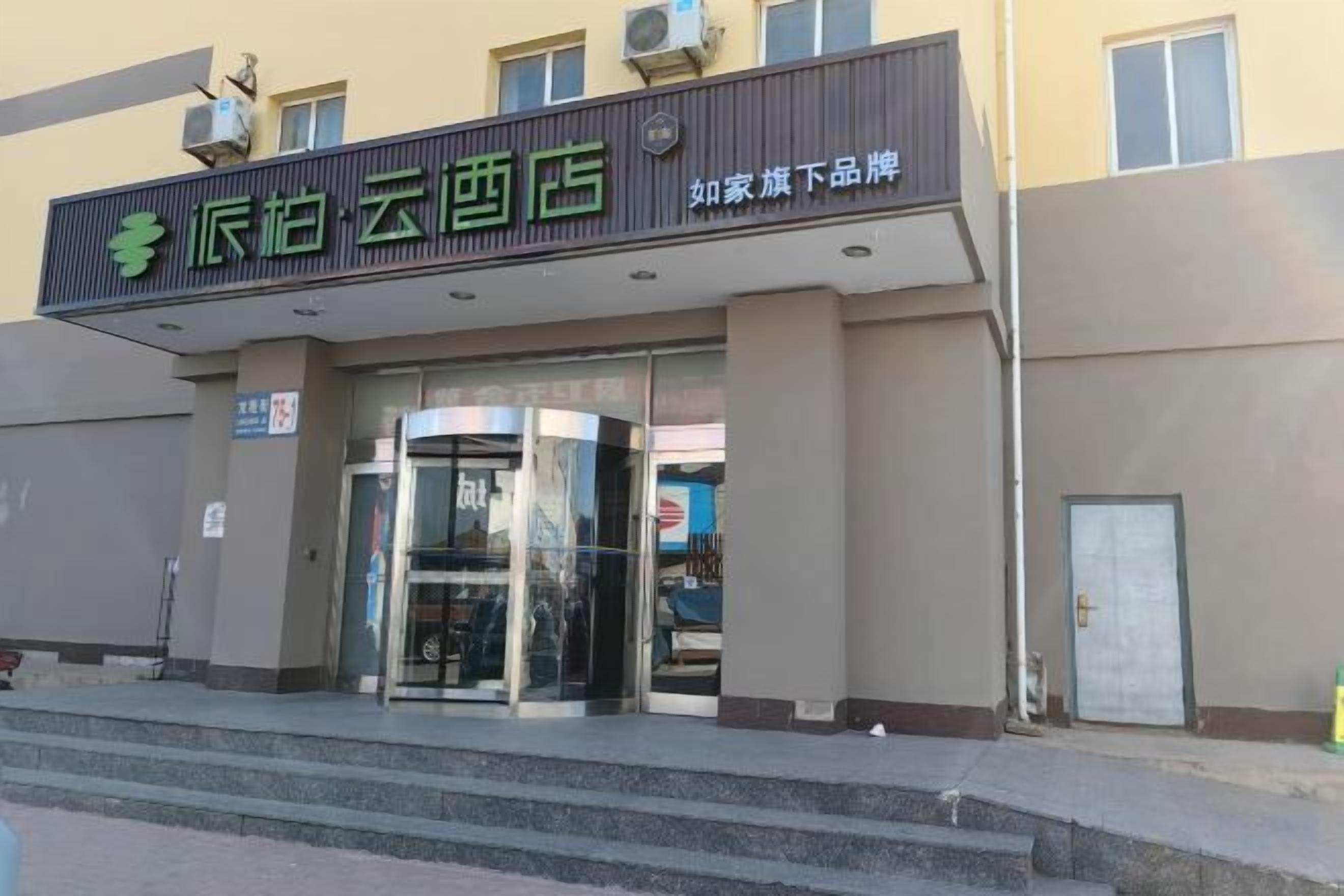 A hotel entrance with a revolving door, a signboard, and a staircase leading up to the entrance.