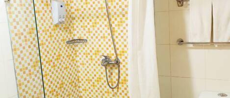 Une salle de bain avec un mur recouvert de carreaux à motifs, une douche équipée d’un pommeau de douche à main, un porte-serviettes avec des serviettes blanches et des toilettes dont on peut voir la marque.