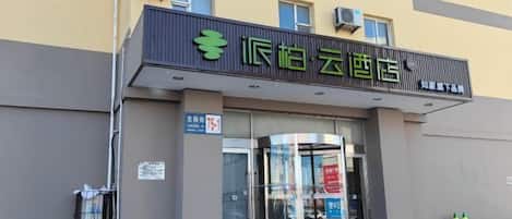 A hotel entrance with a glass door, a signboard, and a staircase leading up to the entrance.