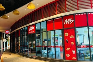 Een restaurant met een rood-wit kleurenschema, met een groot 'Mb'-logo en een 'Merrybrown' bord.