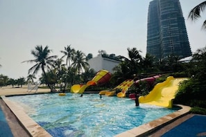 Une piscine avec des toboggans et des palmiers.