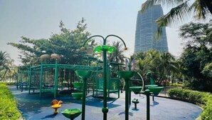 A playground with green play structures and a palm tree in the background.