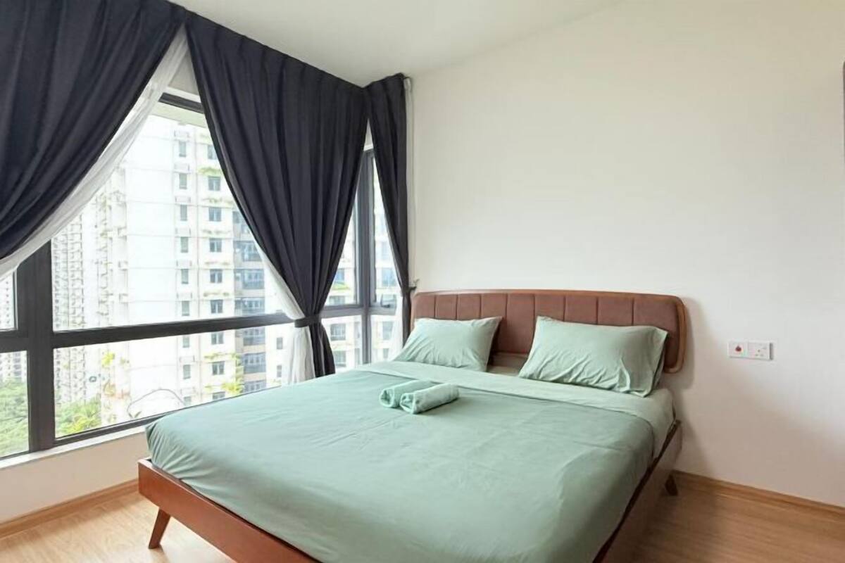 Una camera d'albergo con un letto, una finestra con tende e vista sugli edifici.