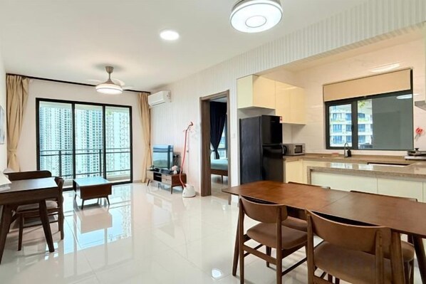 A modern hotel room with a dining area, a kitchen, and large windows.