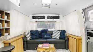 Ein gemütliches Wohnmobil-Interieur mit einer Sofagarnitur, einem Holztisch und einem Bücherregal.