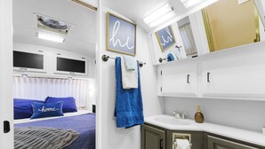 Ein gemütliches Schlafzimmer mit Bett, Fenster und einem Badezimmer mit Waschbecken und Schränken.