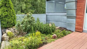 A landscaped garden with various plants and a wooden deck. - Čertovka by Interhome (Harrachov)