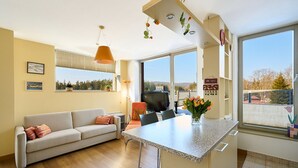 A modern living room with a sofa, a dining table, and a kitchen island. - Čertovka by Interhome (Harrachov)