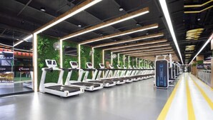 A gym with treadmills aligned in rows, a yellow safety line on the floor, and green wall decorations. - HanTing Hotel (Yueyanglou District Pipawang Overpass) (Yueyang)