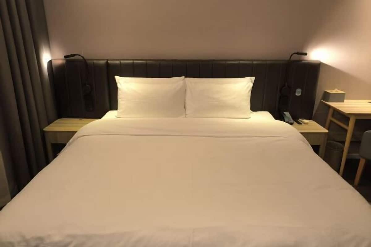Una habitación de hotel con una cama, una mesita de noche, una silla y un escritorio.