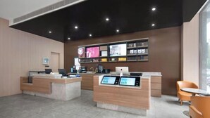 A modern reception area with two counters, digital displays, and a coffee machine. - HanTing Hotel (Yueyanglou District Pipawang Overpass) (Yueyang)