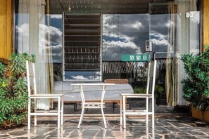 A patio with a table and chairs, a view of the sky through a window, and a sign with Japanese characters.